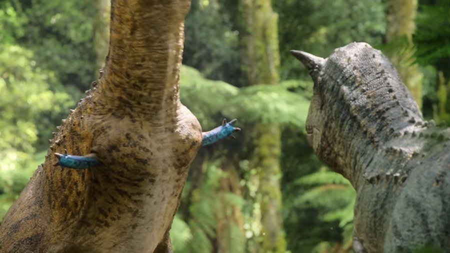 "Planète préhistorique" une capture d'écran d'un Carnotaurus mâle debout là avec ses petites mains bleues attendant qu'une femelle l'essaye.