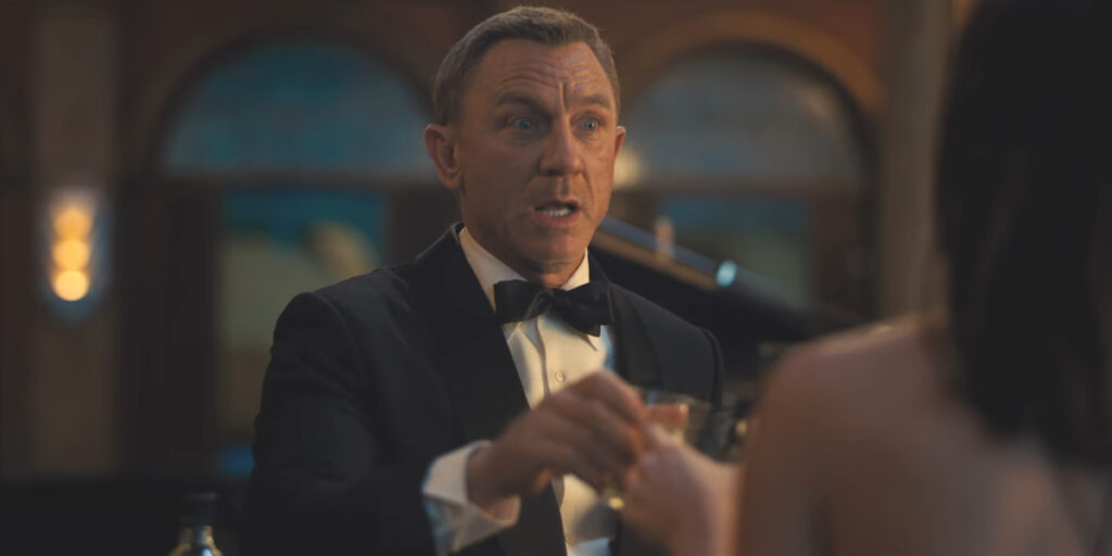 Daniel Craig toasts a drink in a hurry in No Time To Die.