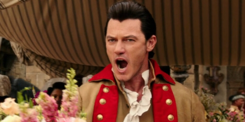 Luke Evans sings confidently while holding flowers in Beauty and the Beast (2017).