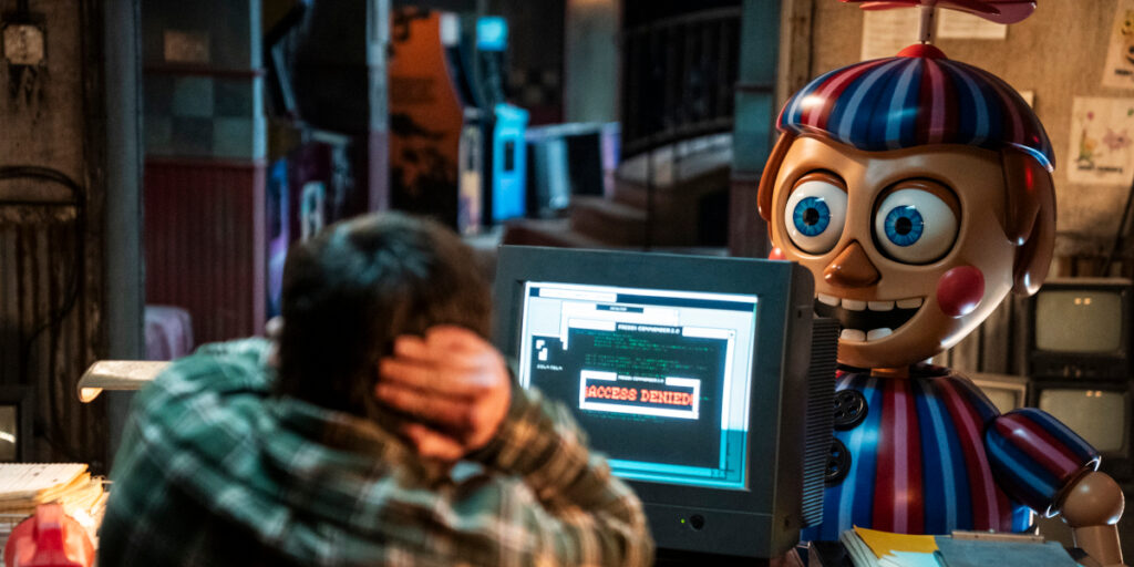 Josh Hutcherson shields his ears as Balloon Boy stands in front of his desk in Five Nights at Freddy's 2.