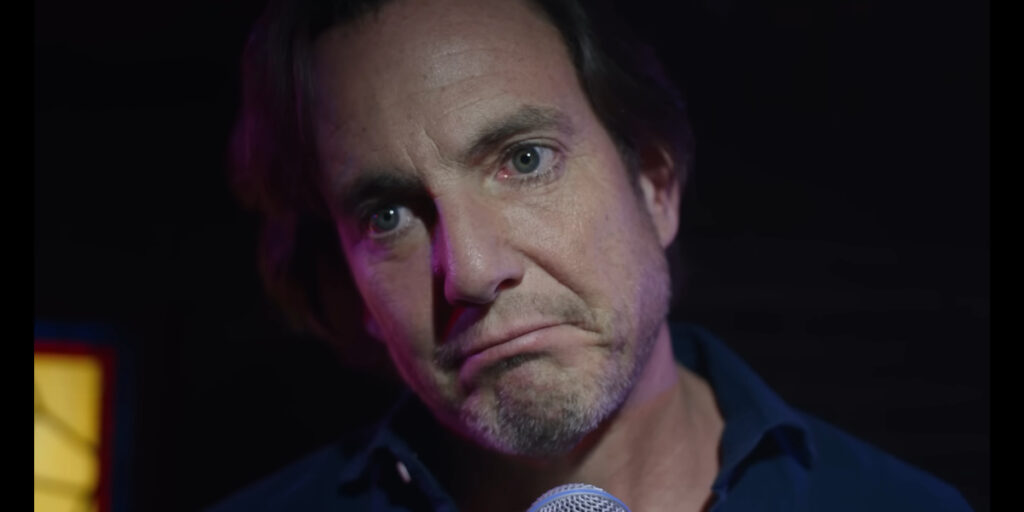 Will Arnett stands at the mic with a forlorn look in Is This Thing On.