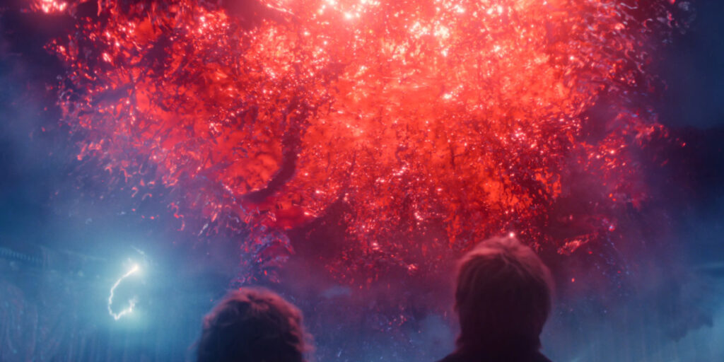 Natalia Dyer and Charlie Heaton look up at a red portal opening in the sky in Stranger Things 5, Vol 2.