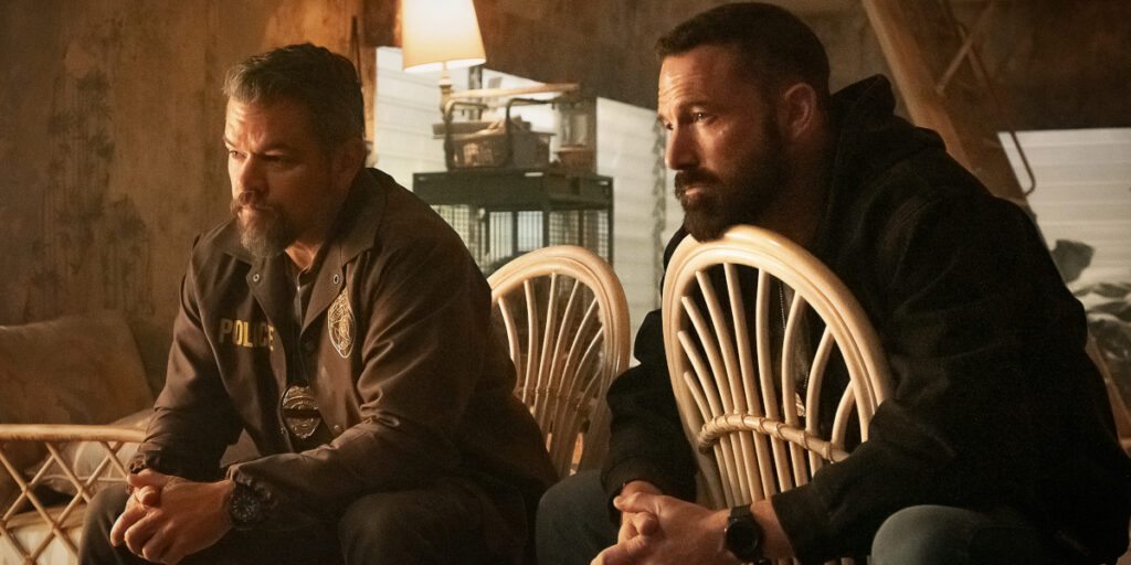 Matt Damon and Ben Affleck sit intently in a run down living room in The Rip.