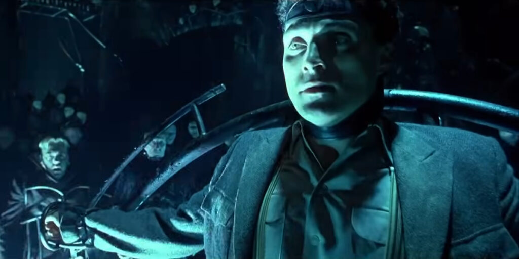 Rufus Sewell confined to a rack while Kiefer Sutherland watches in surprise in Dark City.