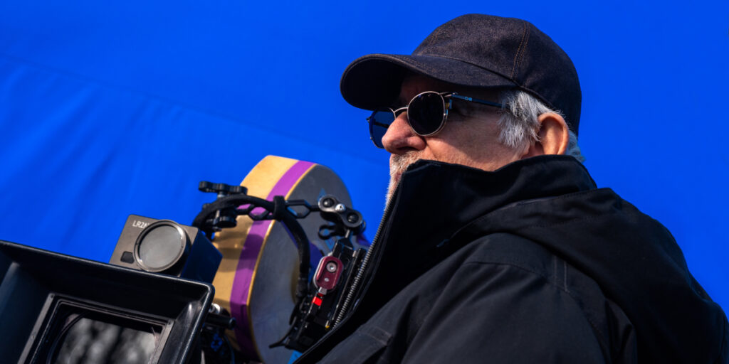 Steven Spielberg stands next to the camera, in front of a blue screen in Disclosure Day.