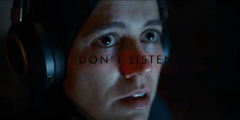 Nina Kiri sits looking disturbed while listening with her headphones in Undertone.