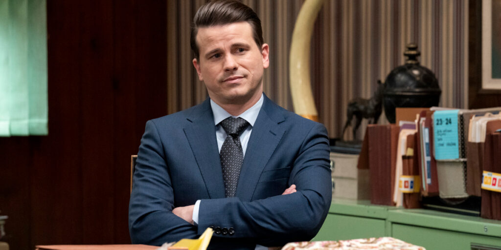 A skeptical Jason Ritter sits with his arms crossed in Matlock S2 E11 - "Tail Lights."