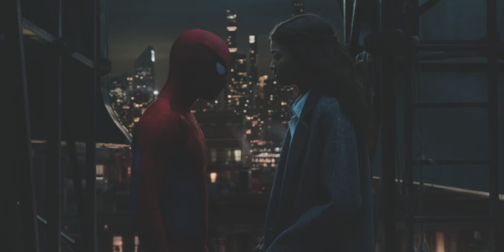Tom Holland stands in his Spidey costume in front of Zendaya on a dark rooftop in Spider-Man: Brand New Day.