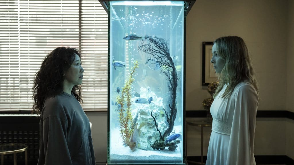 Eve and Villanelle stand separated by a fish tank in Killing Eve _ Season 4, Episode 1 - Photo Credit: Anika Molnar/BBCA