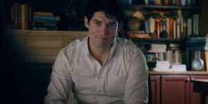 David Corenswet sits in an interview wearing a cocky smirk in Superman.